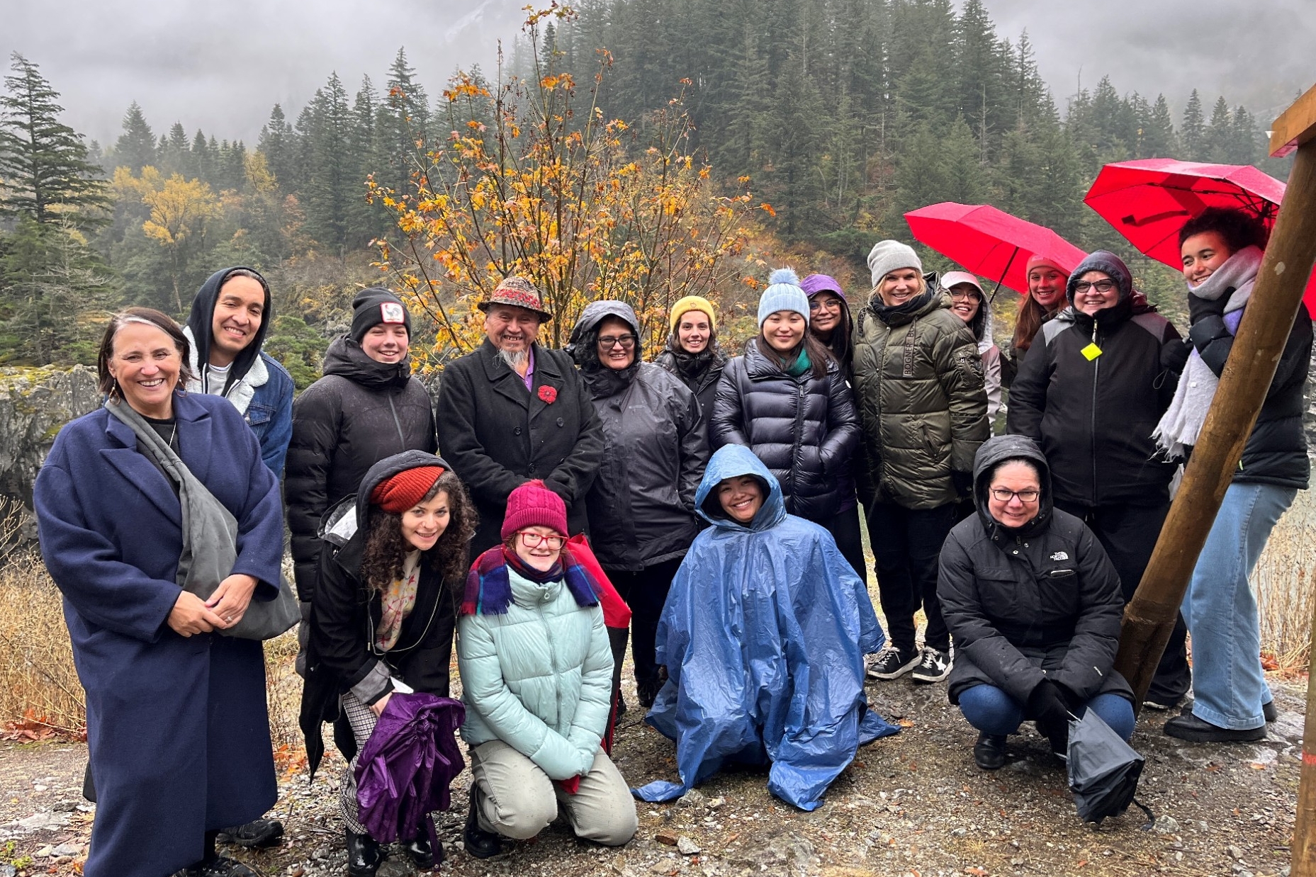 INDG 433 students and faculty outside, under a shelter on a rainy day, listening to Sonny McHalsie on the Stó꞉lō Place Names Tour